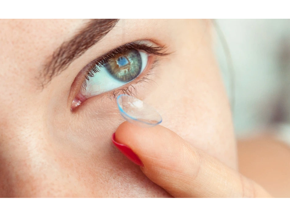 žena pri vkladaní kontaktnej šošovky do oka